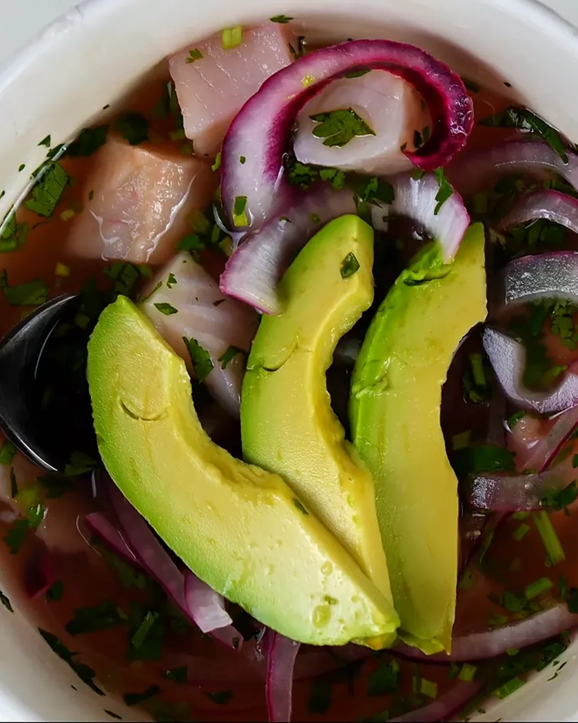 Ceviche de tilapia de cerca: cubos de pescado, cebolla morada en juliana, culantro picado y tajadas de aguacate