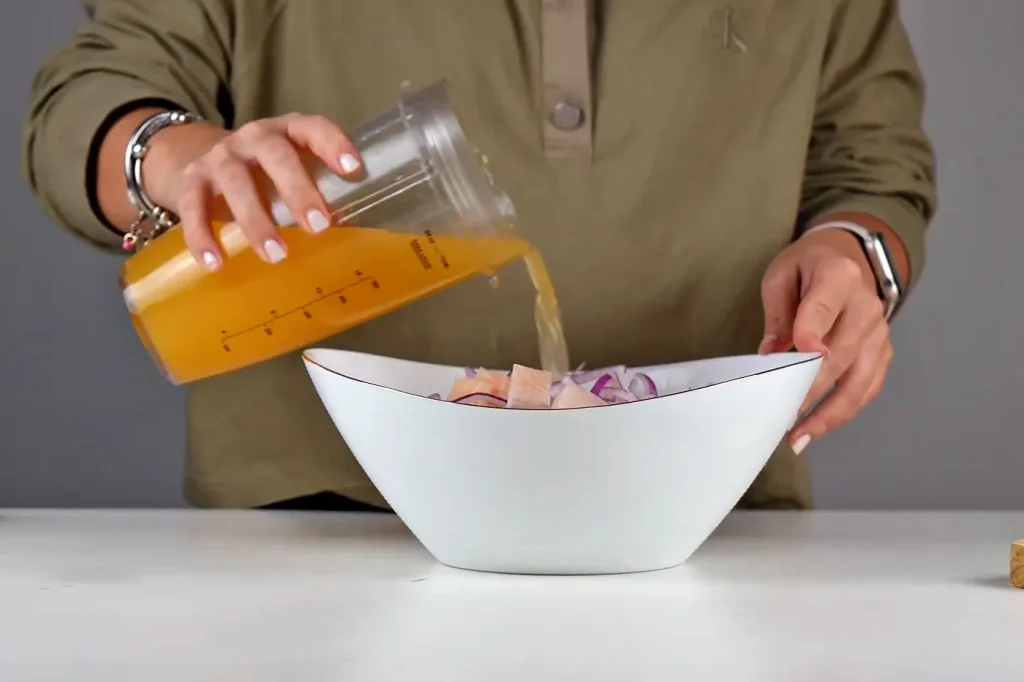 Jugo de limón anaranjado vertido sobre el pescado y la cebolla en el bowl