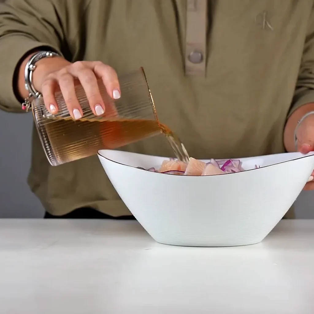 Ginger ale sin azúcar vertido desde un vaso sobre el pescado y la cebolla