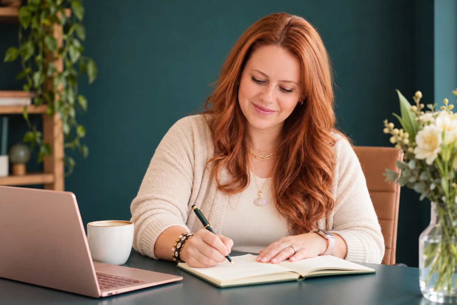 Juliana Campos escribiendo en una libreta en su escritorio, sonriendo