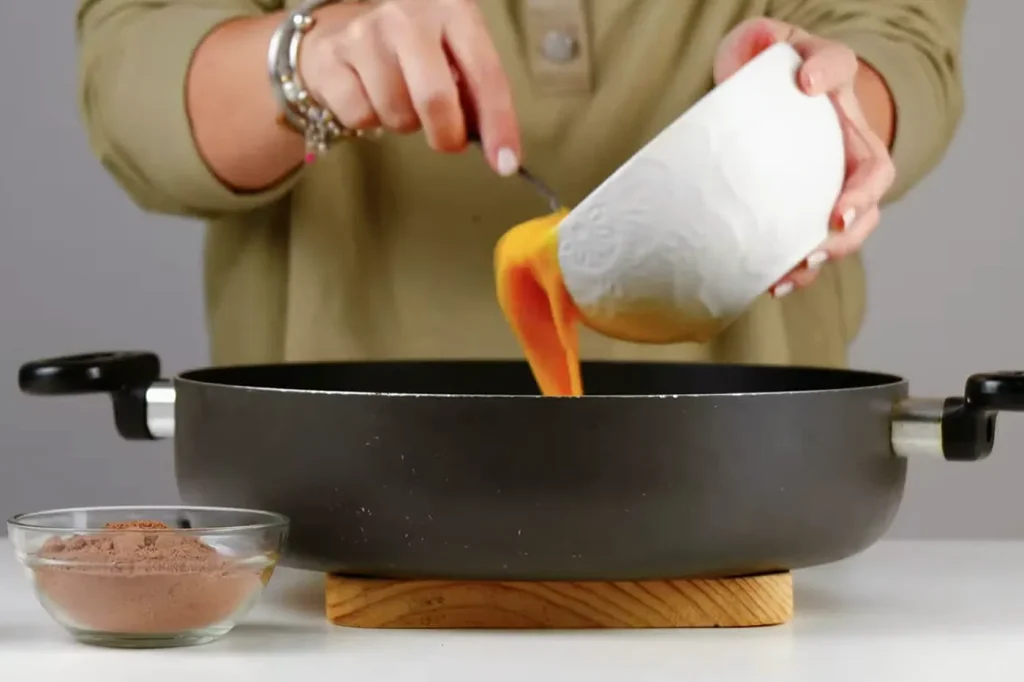 Huevos batidos cayendo del bowl a un sartén antiadherente