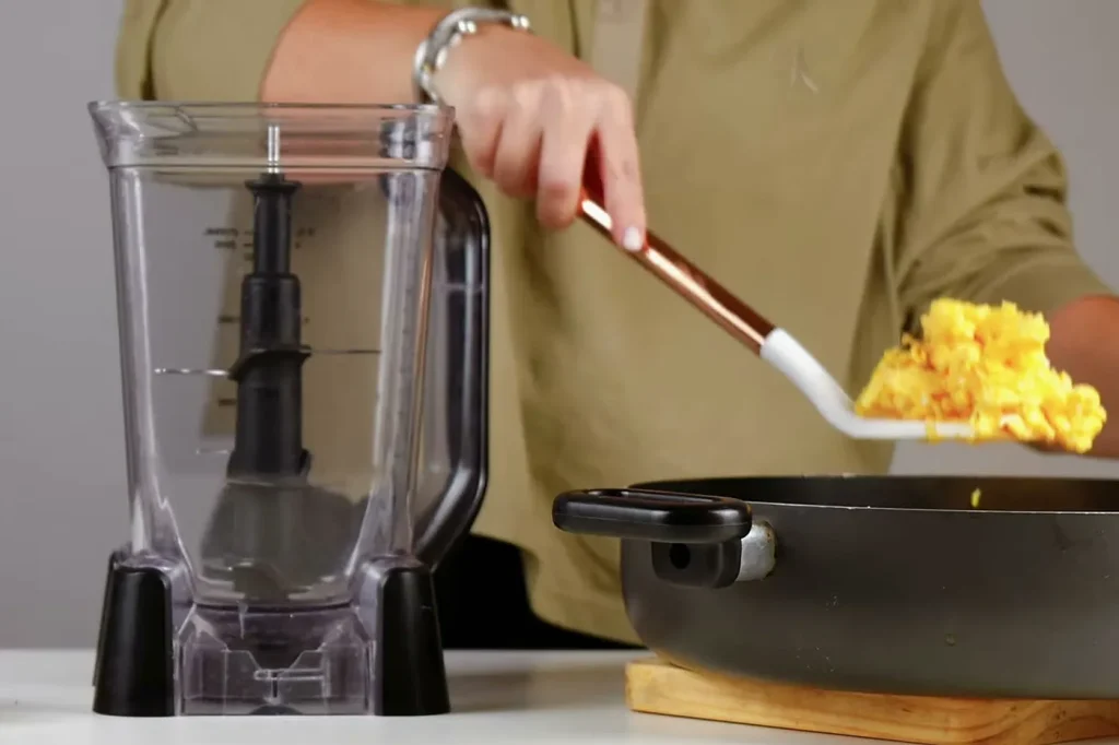 Con la espátula, los huevos revueltos pasan del sartén al vaso de la licuadora