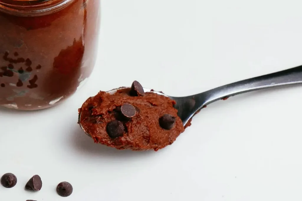 Textura del mousse de chocolate: una cucharada cremosa con chispas de chocolate junto al frasco